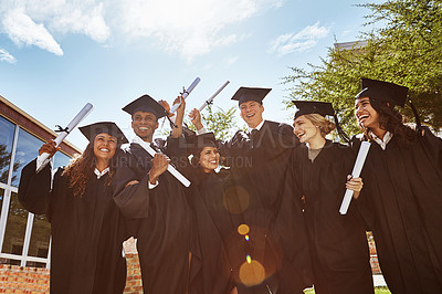 Buy stock photo Portrait of a group of smiling university students holding their diplomas outside on graduation day