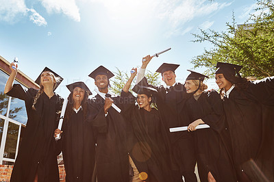Buy stock photo Portrait of a group of smiling university students holding their diplomas outside on graduation day
