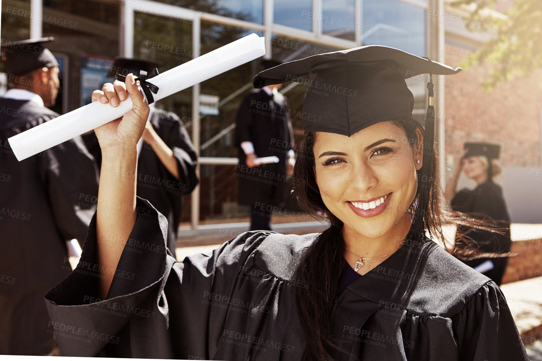 Buy stock photo Portrait of a smiling university student holding her diplomas outside on graduation day