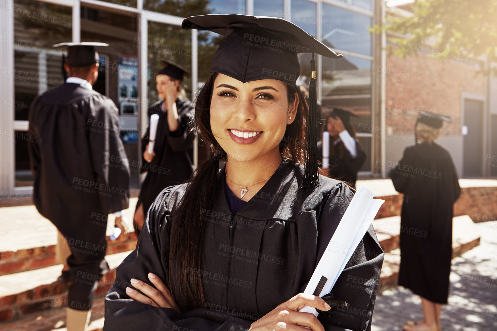 Buy stock photo Portrait of a smiling university student holding her diploma outside on graduation day