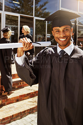 Buy stock photo Portrait of a smiling university student holding his diploma outside on graduation day