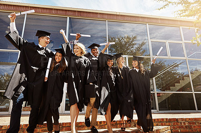Buy stock photo Shot of a group of smiling university students jumping in the air and cheering outside on graduation day