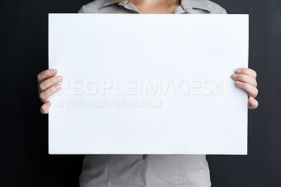 Buy stock photo Shot of a woman holding a blank board against a dark background