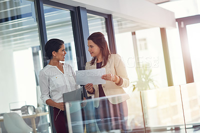 Buy stock photo Shot of businesswomen talking over some paperwork in an office