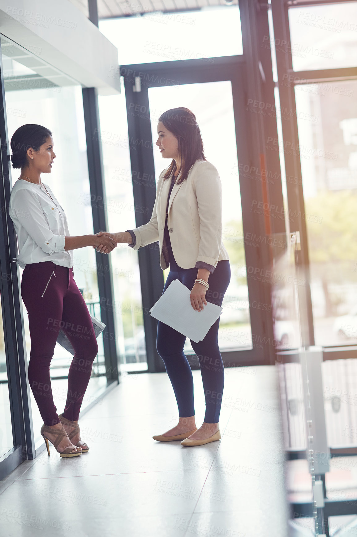 Buy stock photo Shot of two businesswomen shaking hands in an office