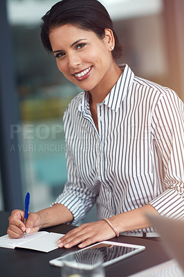 Buy stock photo Portrait of a young businesswoman writing notes at an office desk