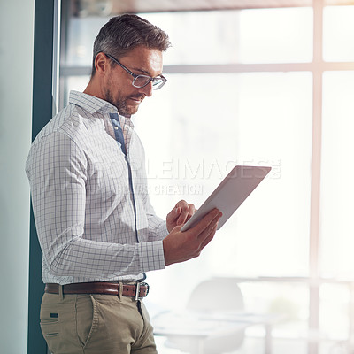 Buy stock photo Shot of a businessman using a digital tablet in an office