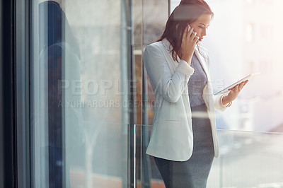 Buy stock photo Shot of a young businesswoman using a phone and digital tablet in an office