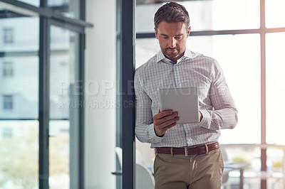 Buy stock photo Shot of a businessman using a digital tablet in an office