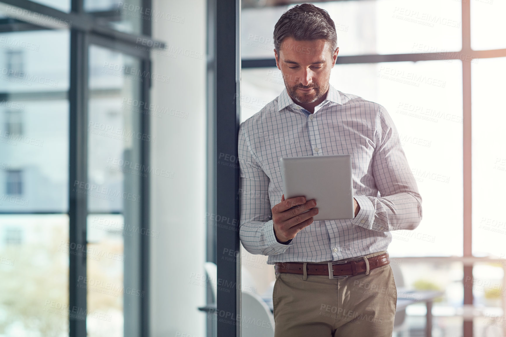 Buy stock photo Shot of a businessman using a digital tablet in an office