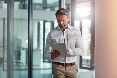 Buy stock photo Shot of a businessman using a digital tablet in an office