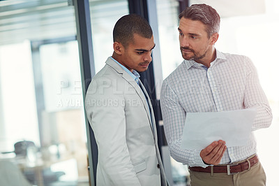 Buy stock photo Shot of businessmen talking over some paperwork in an office