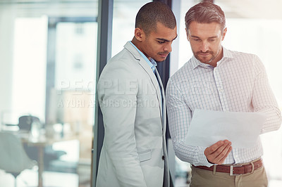 Buy stock photo Shot of businessmen talking over some paperwork in an office