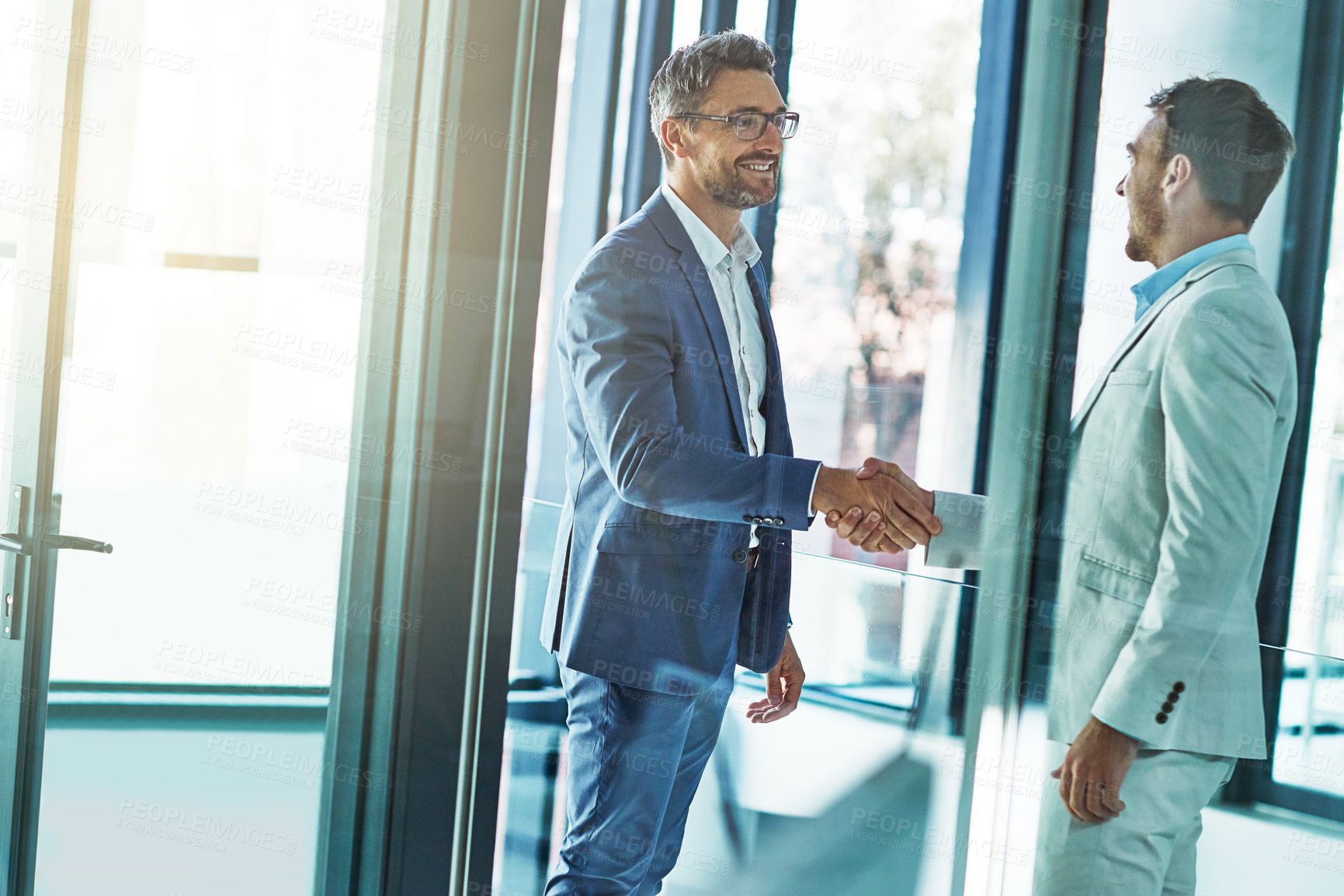 Buy stock photo Shot of two businessmen shaking hands in an office