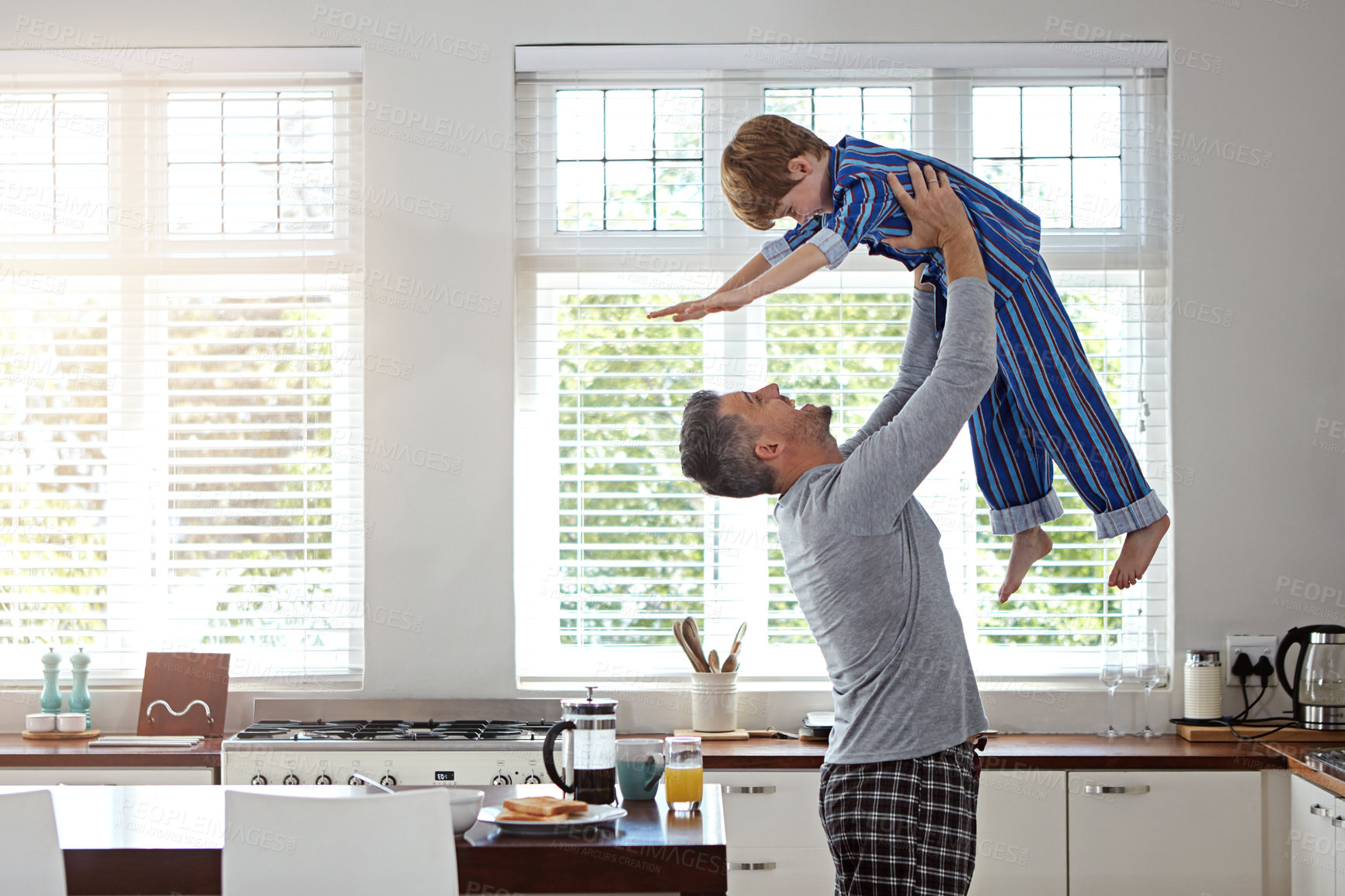 Buy stock photo Kitchen, dad and flying with boy for bonding, fun and love in morning with pajama. Apartment, people and parent for lifting with smile for support, care and playful for child development at home