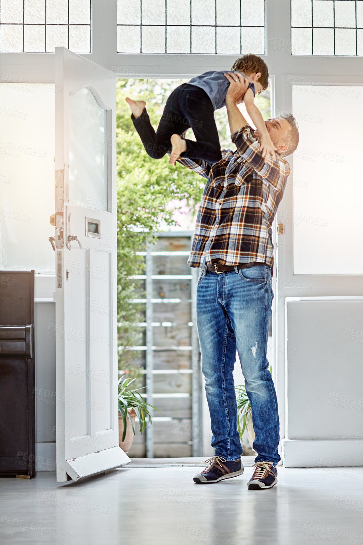 Buy stock photo Family, lifting and father with son at front door for coming home, airplane and game, happy and smile. Man, boy and excited parent return after work, greeting and hug, playing and parenthood moment