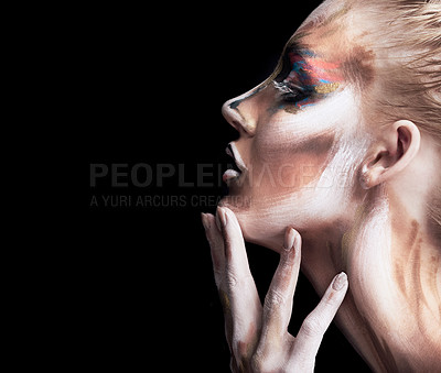 Buy stock photo Studio shot of a young woman posing with paint on her face isolated on black
