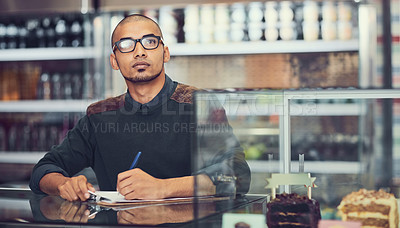 Buy stock photo Shot of a coffee shop owner writing on his clipboard