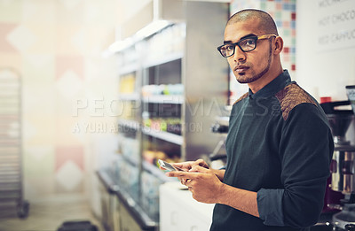 Buy stock photo Shot of a man using his cellphone while standing in a coffee shop