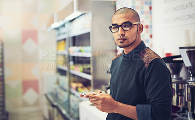 Buy stock photo Shot of a man using his cellphone while standing in a coffee shop