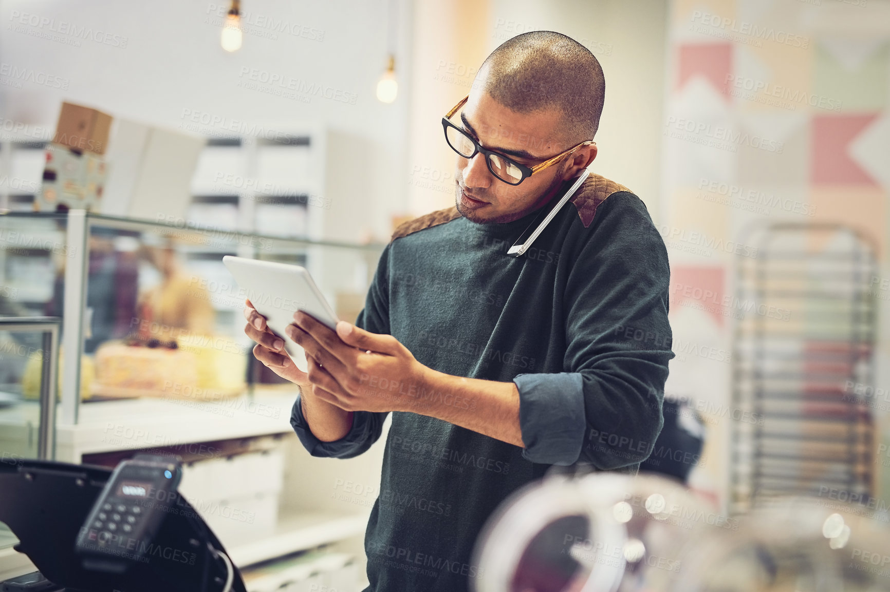 Buy stock photo Shot of a man talking on his cellphone in a coffee shop while using a digital tablet