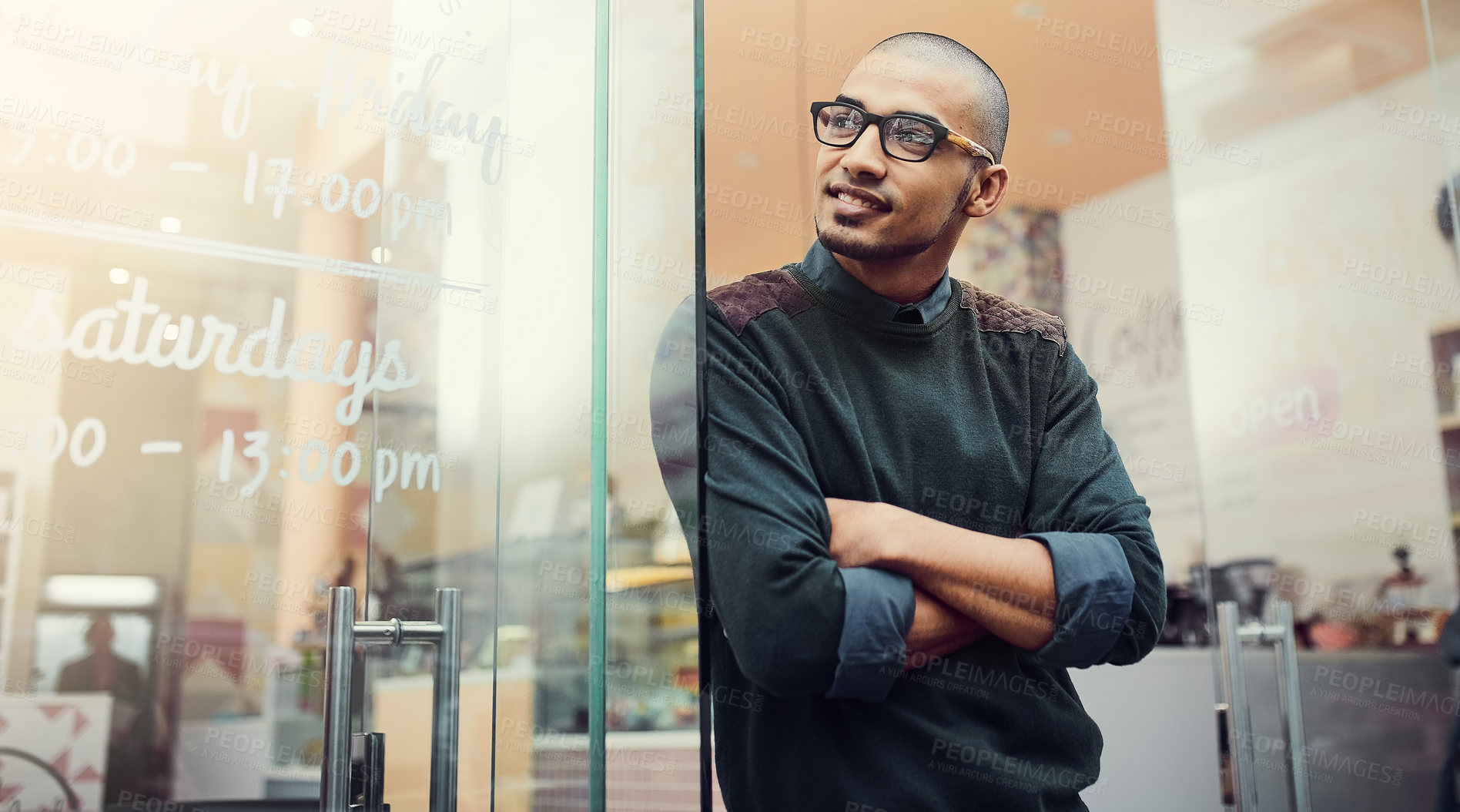 Buy stock photo Shot of a young man standing in the entrance of a cafe