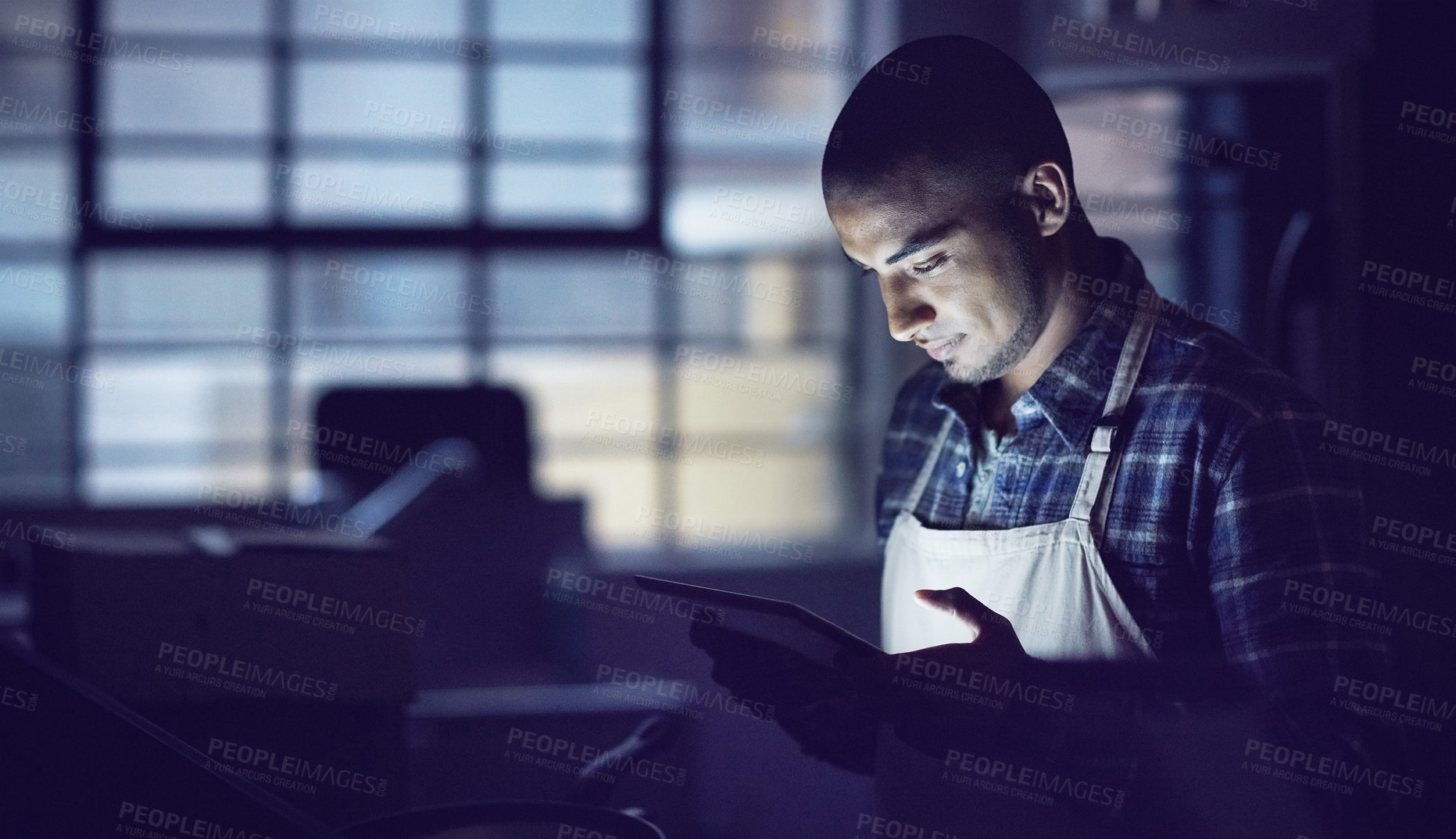 Buy stock photo Shot of a young man working late on a digital tablet in his coffee shop