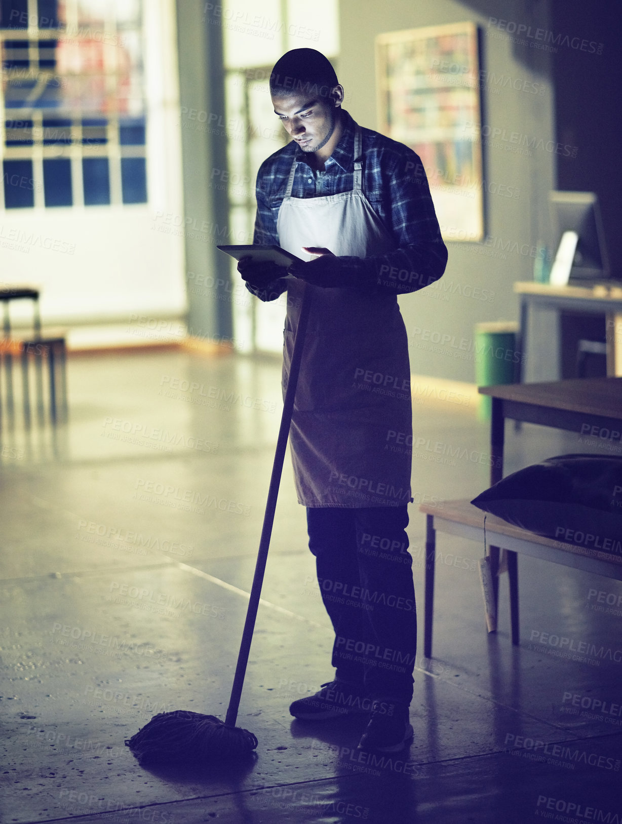 Buy stock photo Shot of a young man working late on a digital tablet in his coffee shop