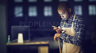 Buy stock photo Shot of a young man working late on a cellphone in his coffee shop