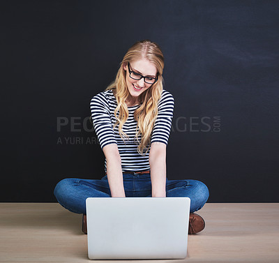 Buy stock photo Studio shot of a young woman using a laptop against a dark background