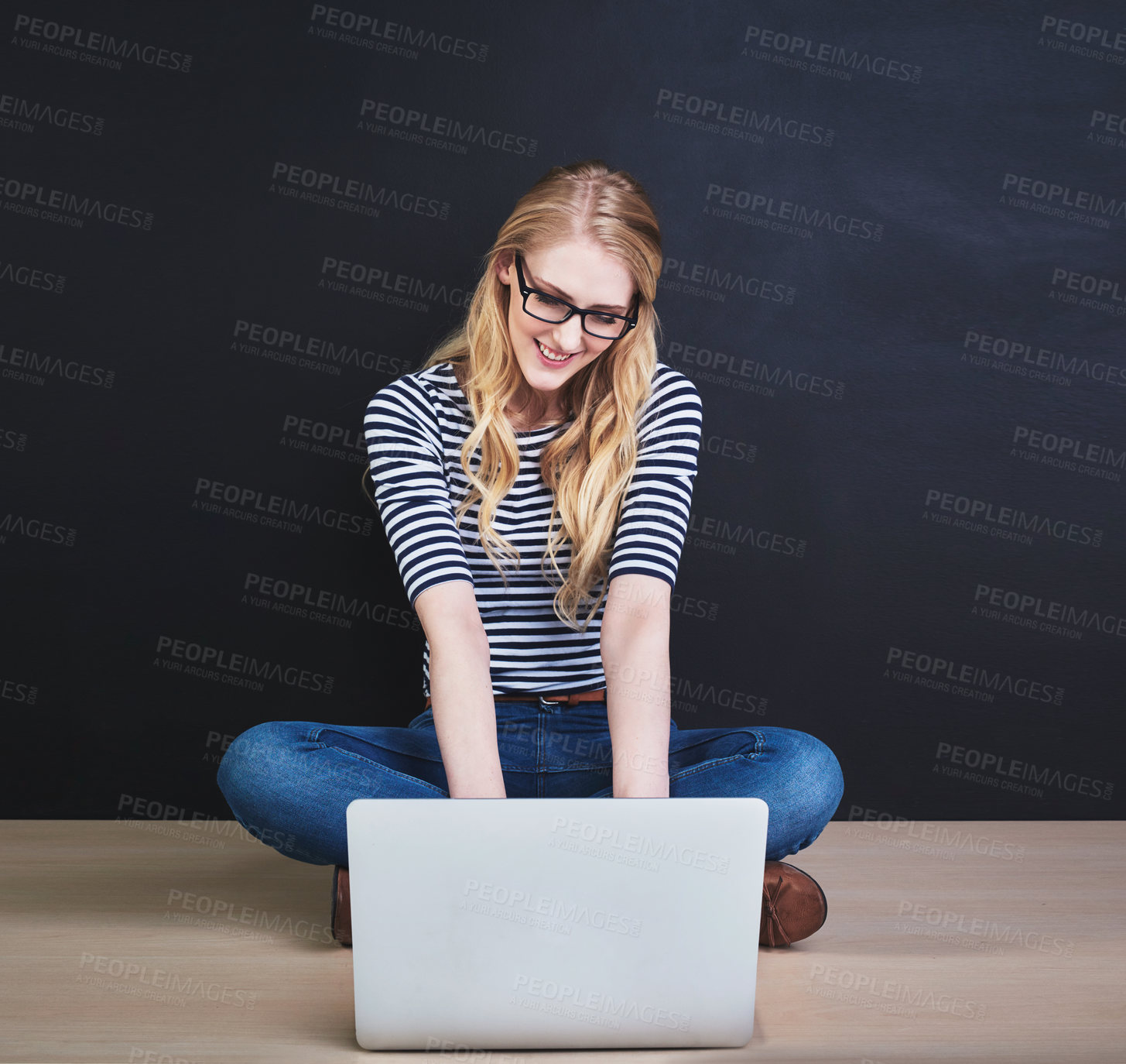 Buy stock photo Studio shot of a young woman using a laptop against a dark background