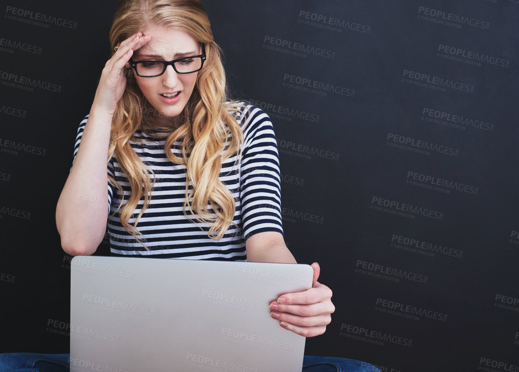 Buy stock photo Studio shot of a young woman using a laptop against a dark background