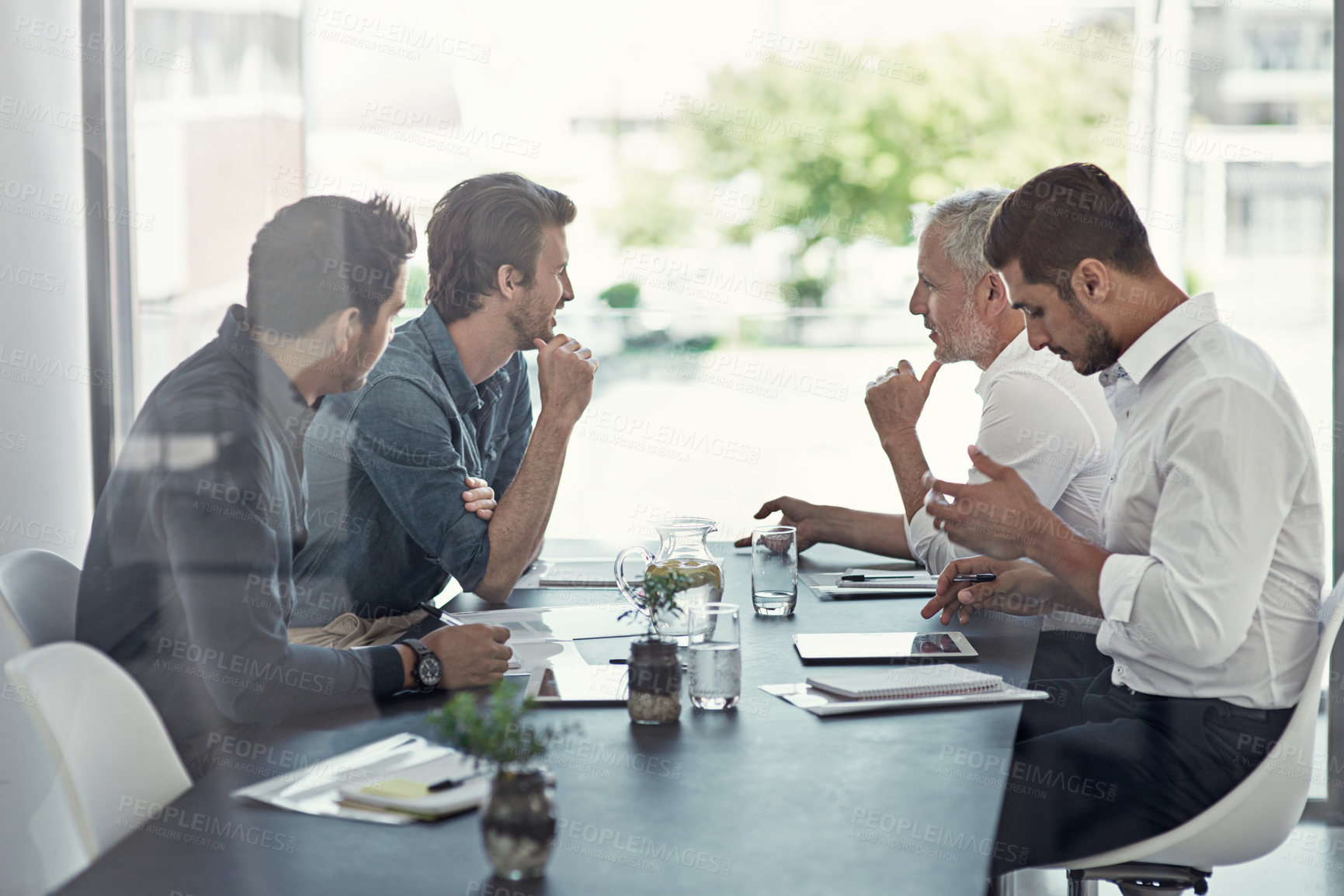 Buy stock photo Shot of a group of businessmen having a meeting around a table in an office