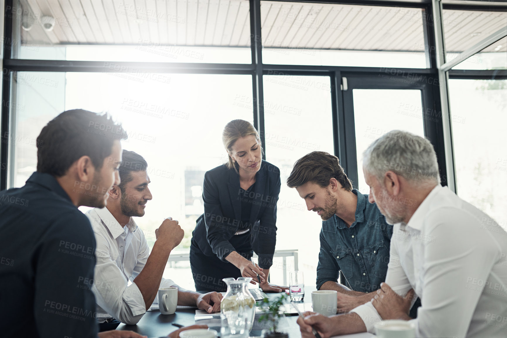 Buy stock photo Shot of a businesswoman talking to colleagues sitting around a table in an boardroom