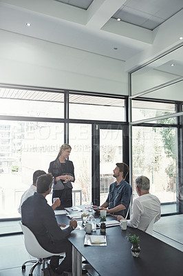 Buy stock photo Shot of a businesswoman talking to colleagues sitting around a table in an boardroom