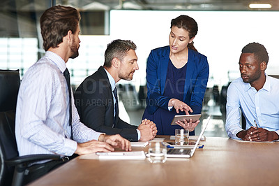Buy stock photo Shot of a group of corporate colleagues talking together over a digital tablet in an office