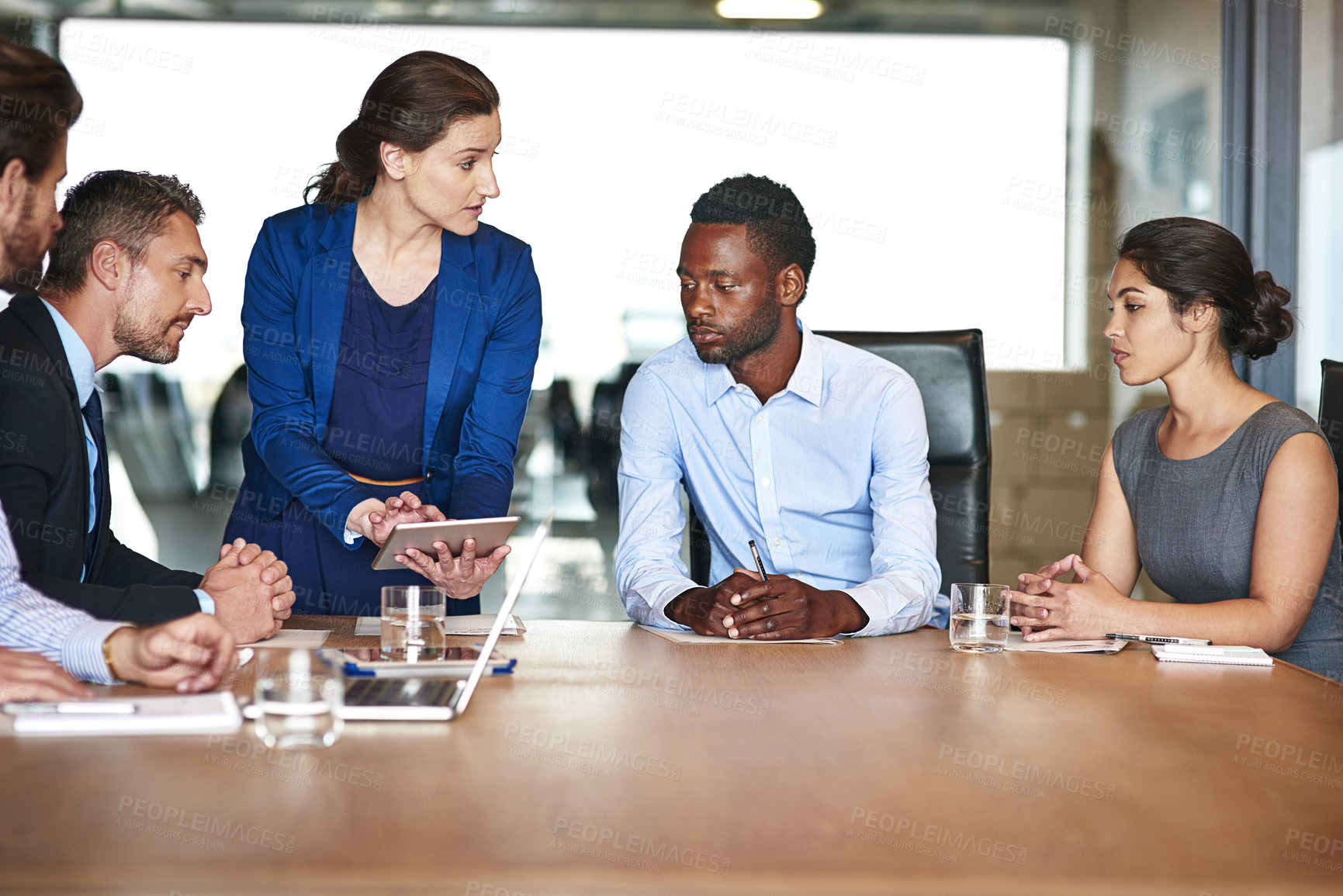 Buy stock photo Shot of a group of corporate colleagues talking together over a digital tablet in an office