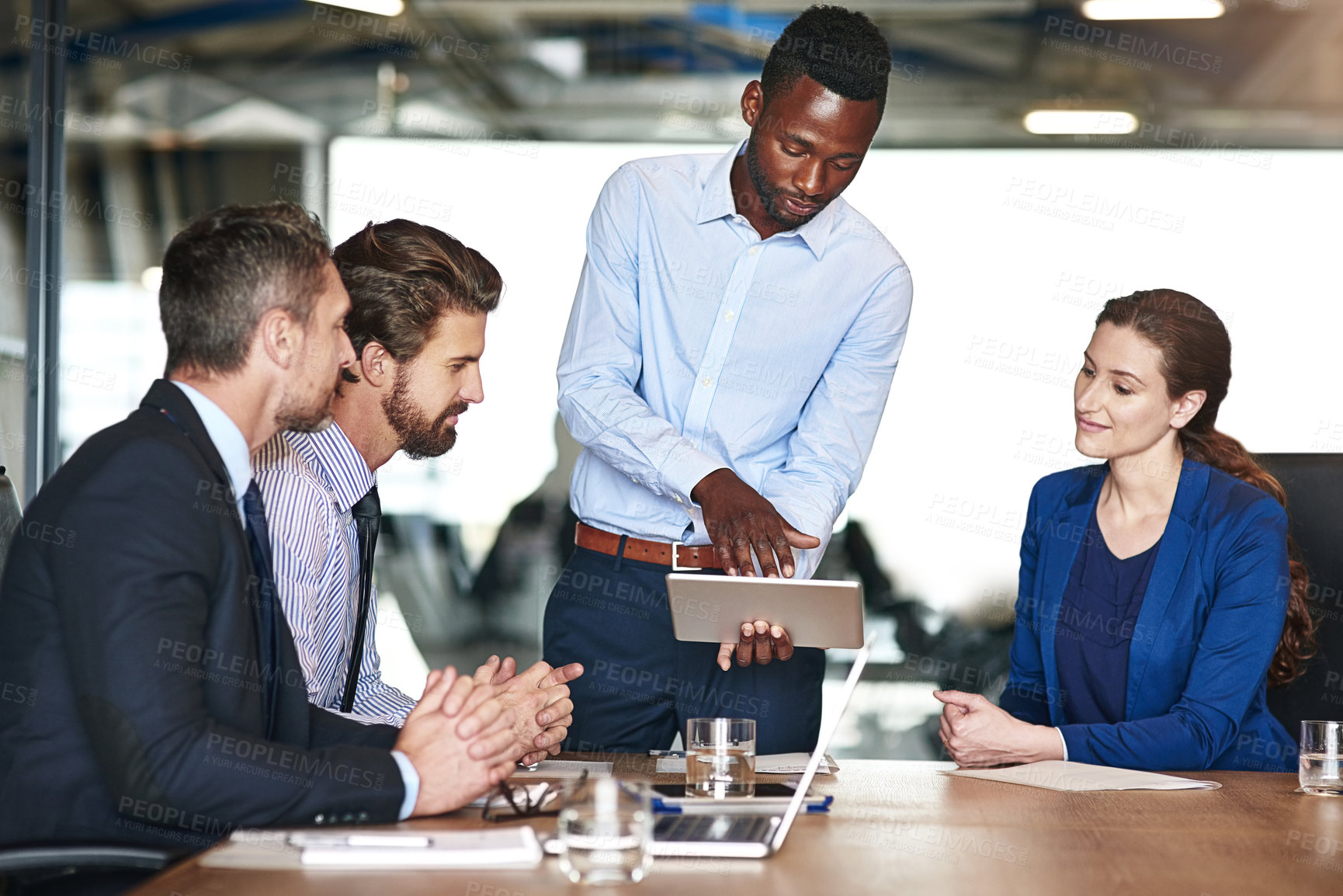 Buy stock photo Shot of a group of corporate colleagues talking together over a digital tablet in an office