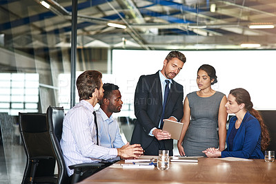Buy stock photo Shot of a group of corporate colleagues talking together over a digital tablet in an office