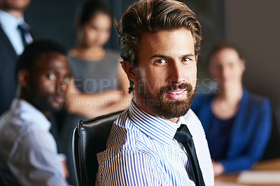 Buy stock photo Portrait of a businessman sitting in an office with colleagues in the background