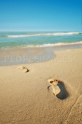 Buy stock photo Footsteps on a sand beach seaside with a white foamy wave from the blue sea. Soft waves of clear water. Sandy beach with human footprints. Pleasing blue sky over a peaceful sea. Sandy tropical ocean.