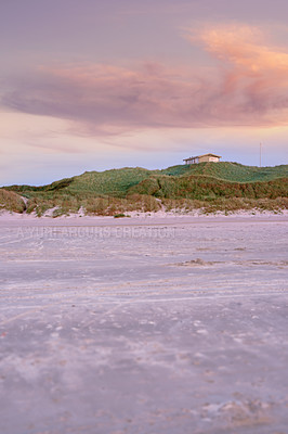 Buy stock photo Landscape of green hills and a tiny house on sand dunes. An empty green mount near the beach with a purple sunset sky and copyspace. A calm and serene remote desert for a holiday retreat and vacation