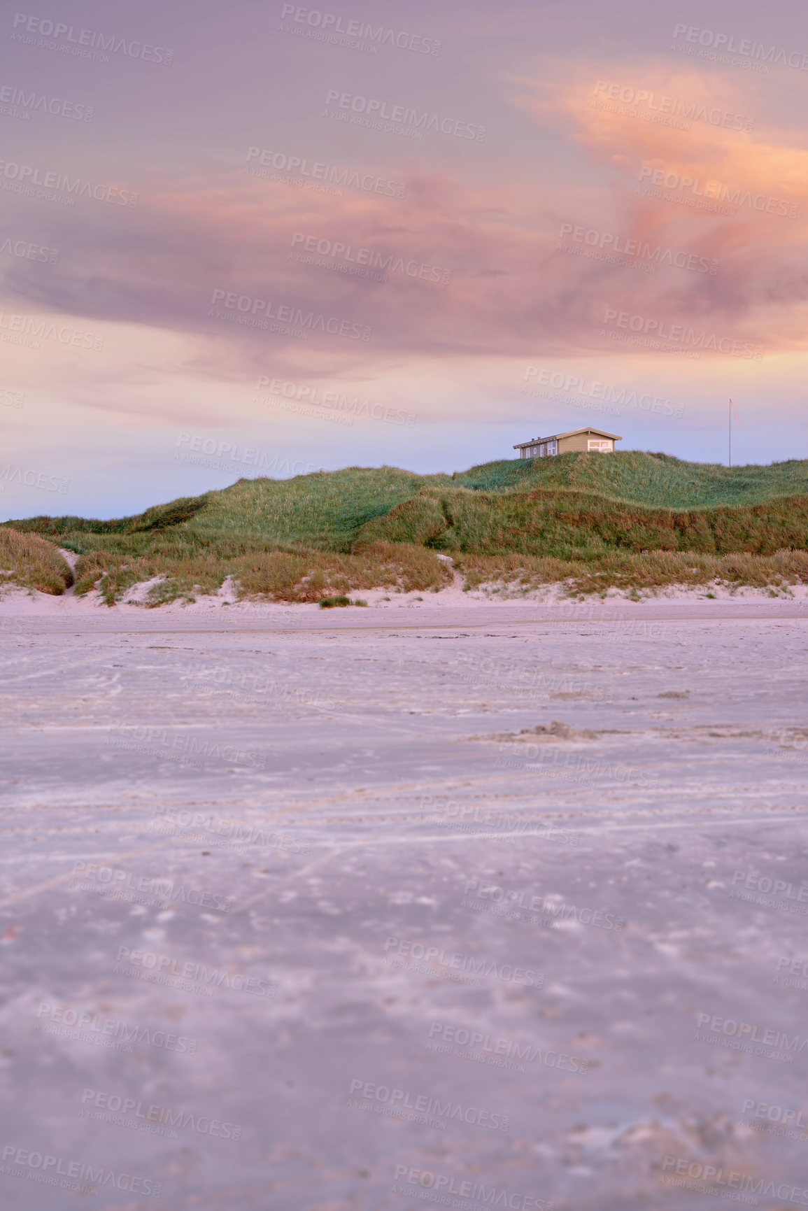 Buy stock photo Landscape of green hills and a tiny house on sand dunes. An empty green mount near the beach with a purple sunset sky and copyspace. A calm and serene remote desert for a holiday retreat and vacation