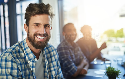 Buy stock photo Portrait of a young businessman sitting in an office with colleagues in the background