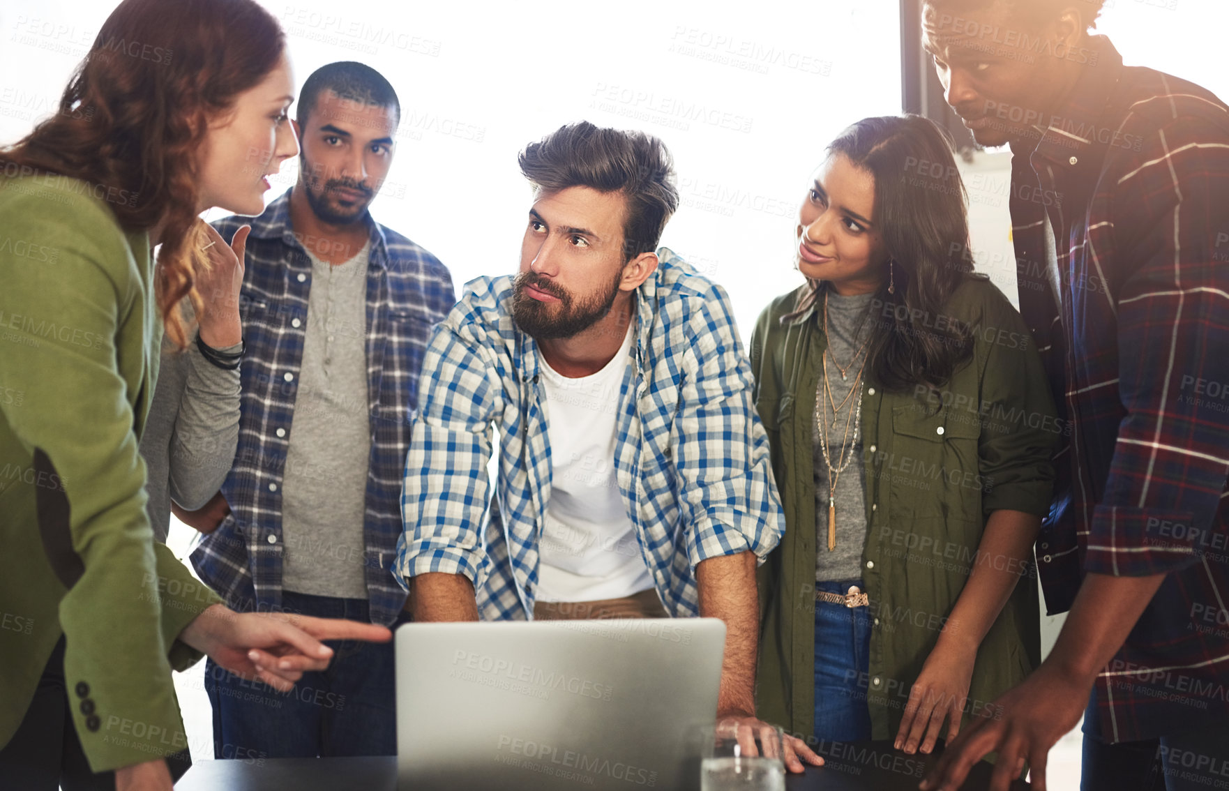 Buy stock photo Shot of a group of colleagues working on a laptop in an office