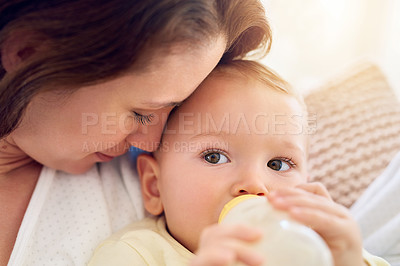 Buy stock photo Shot of a baby drinking his bottle while lying in his mother's arms