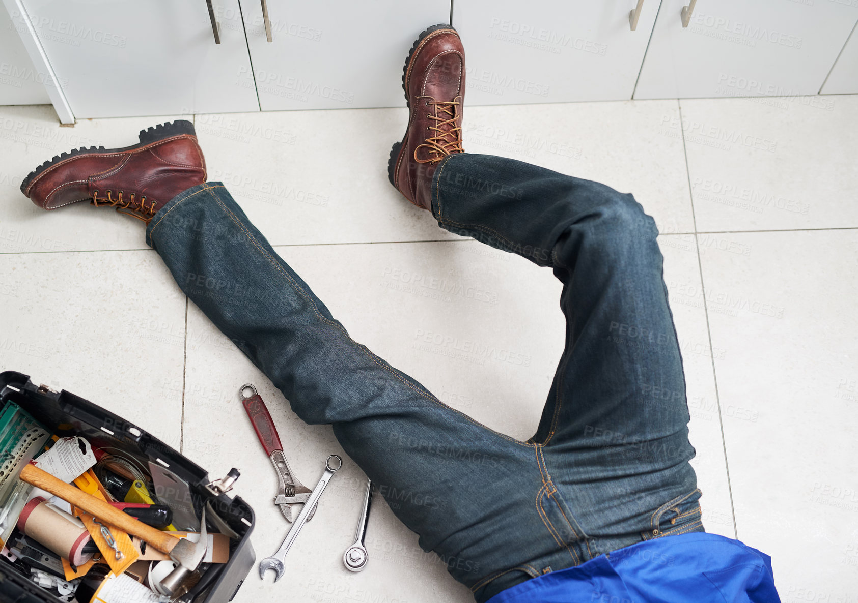 Buy stock photo Cropped shot of a handyman conducting repairs on the floor next to his tool box