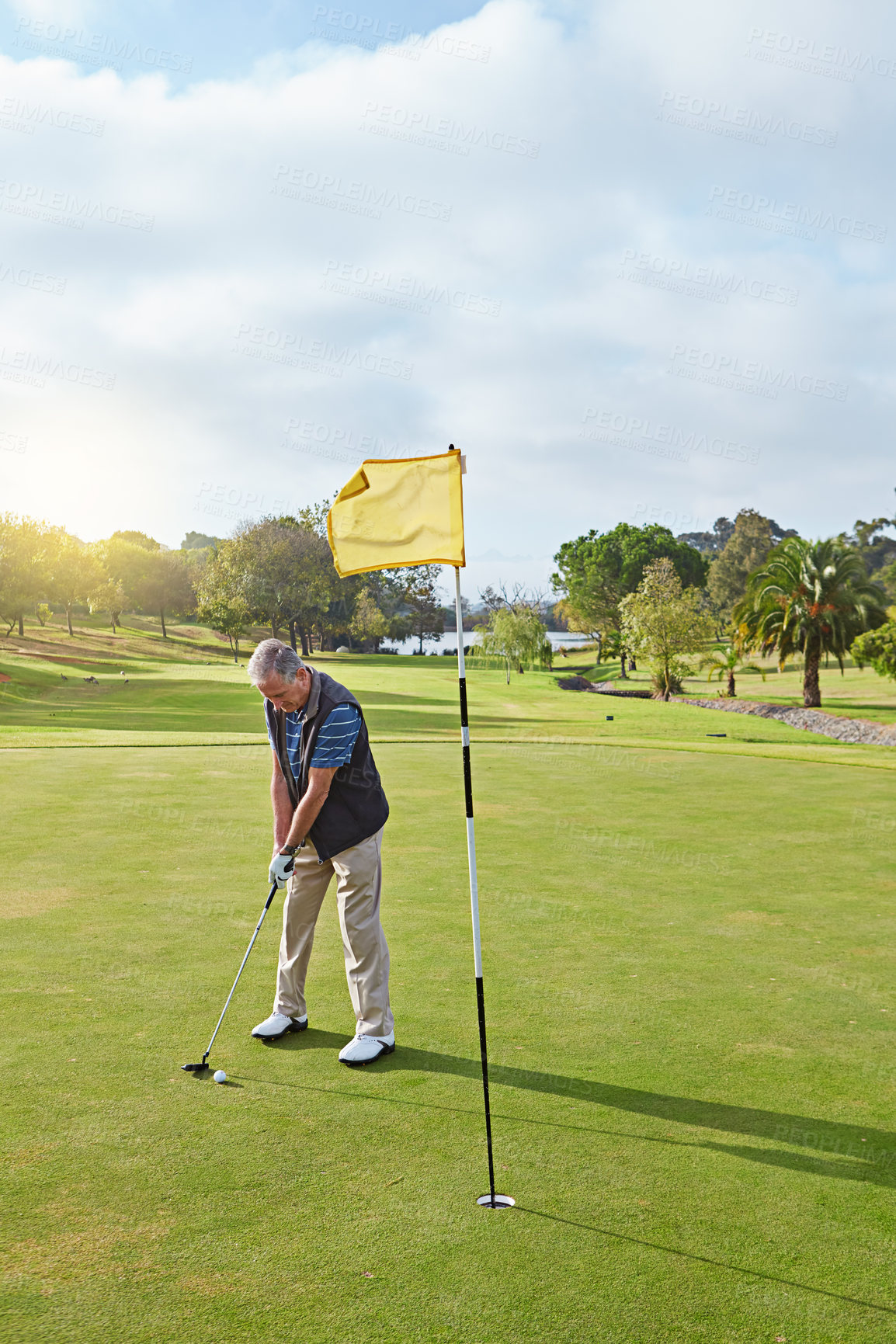 Buy stock photo Full length shot of a senior man lining up a put while enjoying a day playing golf