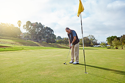 Buy stock photo Full length shot of a senior man lining up a put while enjoying a day playing golf