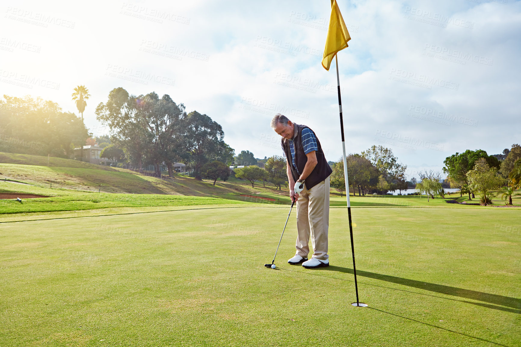 Buy stock photo Full length shot of a senior man lining up a put while enjoying a day playing golf